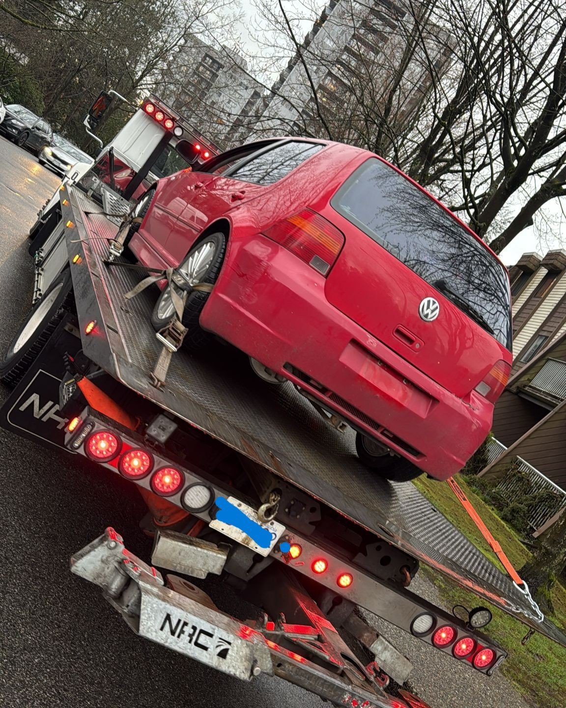 Red convertible car loaded onto a flatbed tow truck