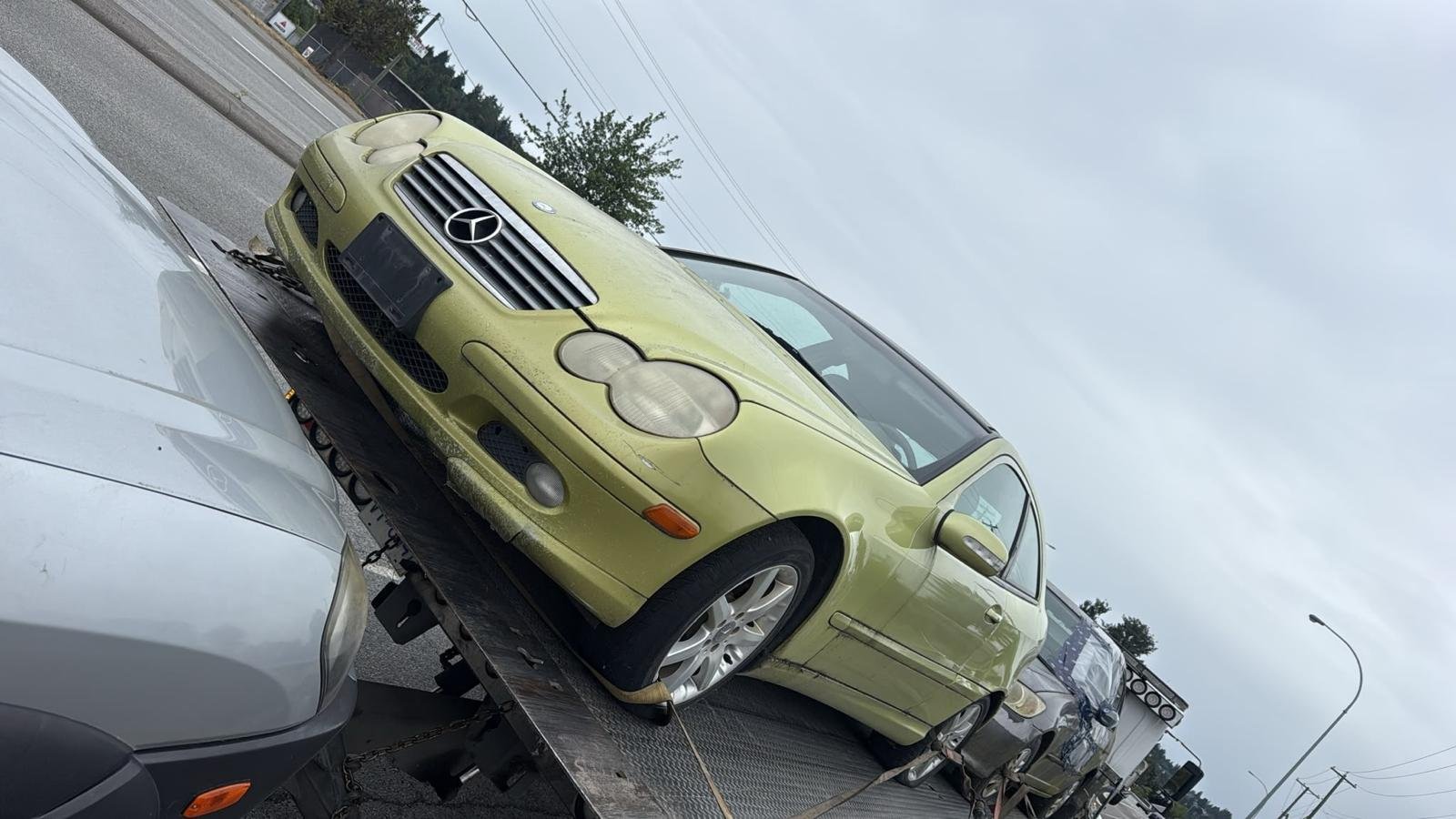 A green car positioned on a flatbed tow truck