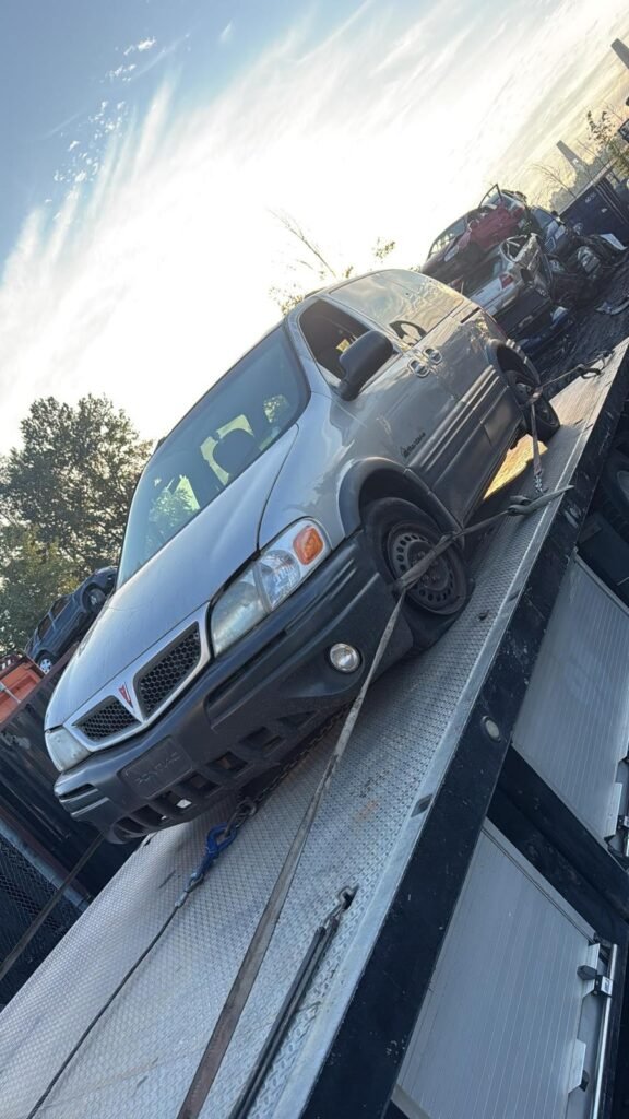 A blue vehicle secured on a flatbed tow truck